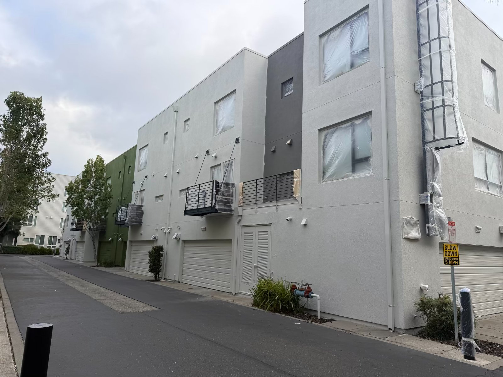 Multi-family townhome exterior repaint in progress with masked windows, Bay Area California